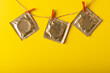 Close-up of condom packages hanging on clothesline with clothespins against yellow background