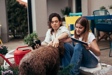 Wall Mural - mother and daughter using digital tablet in backyard while gardening