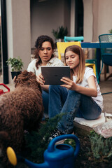 mother and daughter using digital tablet in backyard while gardening