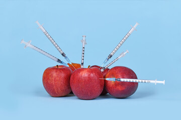 Wall Mural - multiple apple fruits being injected with syringes. concept for genetically modified organism