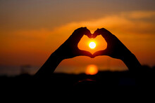 Woman Hands Forming A Heart Shape With Sunset Silhouette.