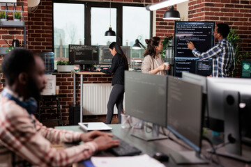 Tech engineers team leader pointing out mistake in application source code. Software developers standing near vertical screen talking about interface bug and slow rate of processing data.