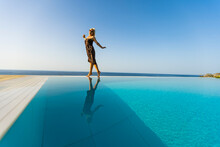 An Attractive Young Woman Stands Near The Pool With A Panoramic View.