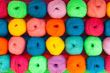 Many Multi-colored Balls Of Threads On A Knitted Fabric, Close-up.