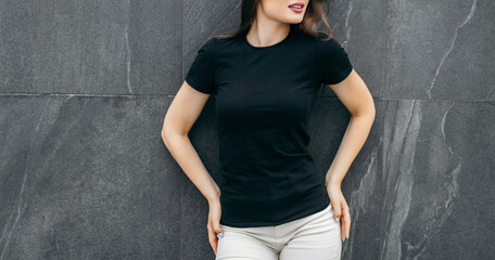 Wall Mural - Stylish brunette girl wearing black t-shirt posing against street , urban clothing style. Street photography	
