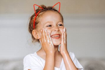 Beautiful young girl washes her face in bathroom at home. Empty space for text.