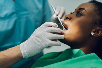 Dentist providing dental care treatment to a african american female patient