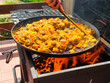 Closeup of a paella a traditional Spanish Mediterranean rice dish on a fireplace, firewood, charcoal cooking way