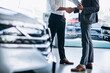 Man shaking hands with car dealer in a car showroom