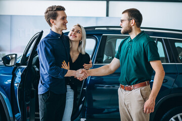 Couple choosing  a car in a car showroom and talking to the dealer