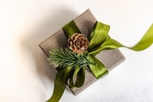 Overhead View Of A Gift Box Decorated With A Green Ribbon, Fir Sprig And Pinecone