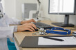 Medicine doctor's working table. Doctor's workspace working at computer and typing electronic medical record sitting near stethoscope and clipboard. Medicine concept. Focus on stethoscope. Close up.