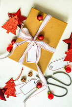 Overhead View Of A Christmas Gift, Tied With A White Ribbon, Christmas Tree Gift Tags And Christmas Baubles