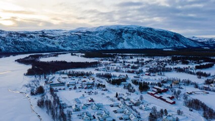 Wall Mural - Alta, Norway. Aerial view of small northern town Alta, Norway in winter. Aerial time-lapse with houses, river and mountain in the evening, zoom in