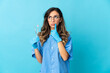 © luismolinero - Woman dentist holding tools over isolated on blue background having doubts while looking up
