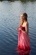 © евгений ставников - a girl in a red dress is standing in the water.beautiful model on vacation in the lake.