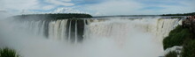 Panoramic View Of Many Majestic Powerful Water Cascades With Mist And Reflection Of Blue Sky With Clouds.