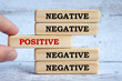 Negative and positive text on wooden blocks with hand placing a wooden block in the middle.