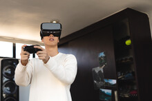 Asian Teenage Boy Using Virtual Reality Simulator And Playing Video Game While Standing At Home