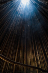 Wall Mural - Wooden tipi with smoke going through the whole in roof. Conical light wooden medieval building with fireplace in the middle. View from inside looking up.