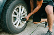 © Maria Manco/Stocksy - man changes tire on car