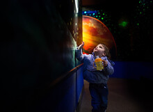 Little Boy Points At Paintings Of Universe