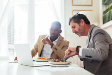 Senior Businessman Having Lunch With Thoughtful Black Colleague