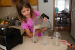 © Maria Manco/Stocksy - child pours green smoothie into cups