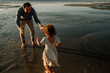 © Erin Brant/Stocksy - Father reaching for daughter on sea shore