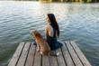 © Demetr White/Stocksy - Girl with dog sitting on bridge near river