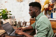 © BONNINSTUDIO/Stocksy - Serious black man using laptop in flower shop