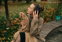Woman Enjoying Music In Autumn Park