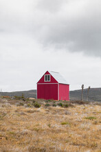  Red Wooden House In The Middle Of A Field With A Gray Sky