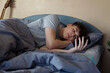 © Danil Nevsky/Stocksy - Melancholic guy lying on bed and using smartphone