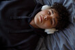 © Danil Nevsky/Stocksy - Sleepy guy lying on bed and listening to music