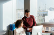 © David Prado/Stocksy - Happy colleague couple using computer in office desk