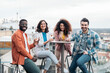 © Santi Nuñez/Stocksy - Cheerful multiethnic friends standing on rooftop