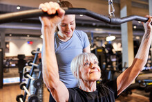 Smiling Senior Woman Lifting Weights With A Trainer