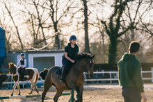 Young Women Practicing Horse Riding With Trainer