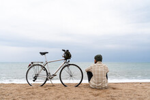 Man Overlooking The Sea With Bike Parked