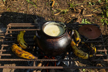 A Clay Pot With A Beverage Inside And Bananas On A Grill
