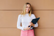 © VICTOR TORRES/Stocksy - Pretty young girl holding folder over brown wall