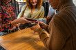 © Manu Prats/Stocksy - Diverse women paying phone in clothes shop