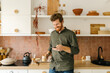 © STUDIO TAURUS/Stocksy - Happy man having cup of coffee and looking at phone