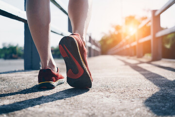 Woman wear running shoe on to walking and running on nature green background.Health exercise.