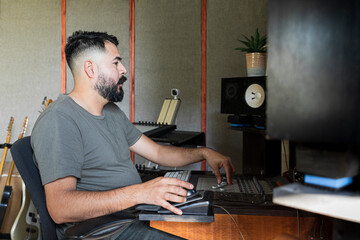 Bearded latino man moving buttons in front of an audio console
