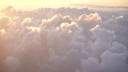 Wall Mural - aerial view of sunny orange and pink huge fluffy white clouds during sunrise time as seen gthrough w