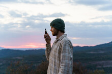 Portrait Of Happy Man In Nature At Sunset Using Phone