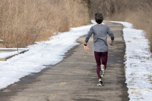 A Lone Male Jogger Sweats Lightly As He Makes Way Down A Long Nature Trail On An Overcast, Winter Day.