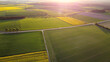 Drohnenaufnahme von schönen Feldern im Frühling mit Straße und Sonnenuntergang